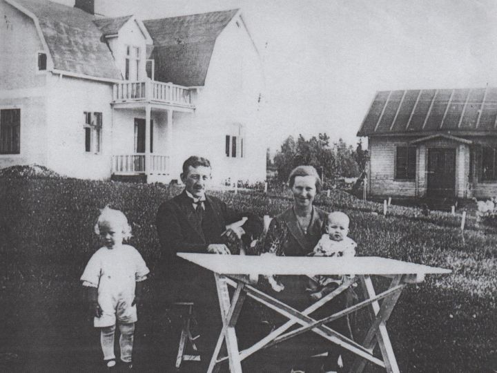 Bild föreställandes familjen Svensson med grundaren Erik Svensson och hans familj, svartvitt foto av familjen sittandes vid trädgårdsbord framför sitt hem i Småland.