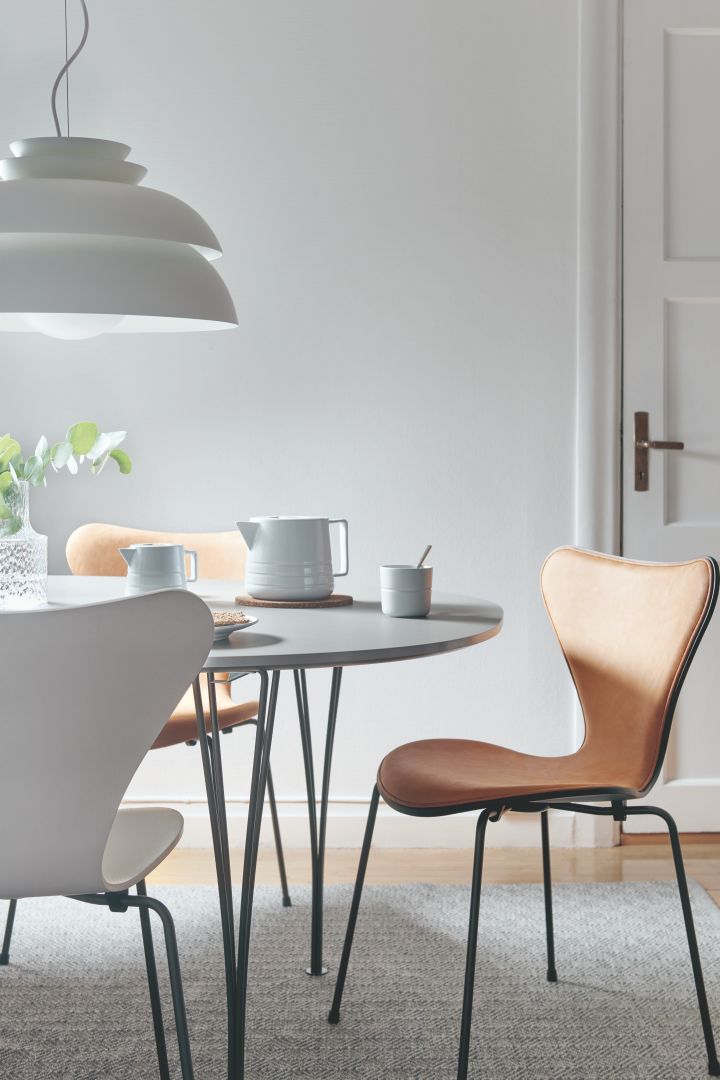 Matplats-inspiration i tidlös design här med Super elipse bord i grått från Fritz Hansen tillsammans med Sjuan-stol i brunt skinn. Bordet är dukat medLines porslin i vitt från NJRD. Över bordet hänger Concert P3 pendel i vitt.