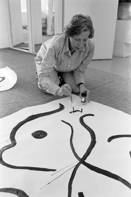 Porträtt av Marimekkos grundare Armi Ratia, sittandes på golvet där hon handmålar ett mönster.