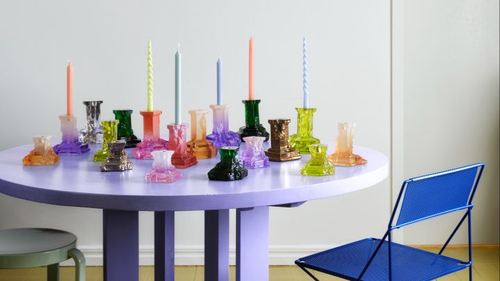 Rocky Baroque-serien av Hanna Hansdotter består av kolonn-liknande ljusstakar i massivt glas som färgats på unika sätt i olika färger. Här samsas hela kollektionen på ett lila, runt bord.