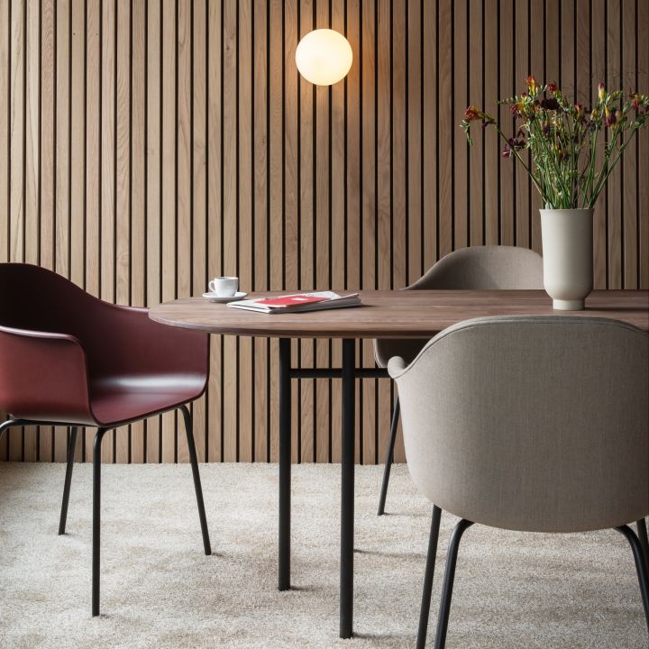 Snaregade ovalt matbord från Menu har en minimalistisk, modern design som rymmer många stolar, tillverkat i svartbetsad ek med underrede i lackerad metall.