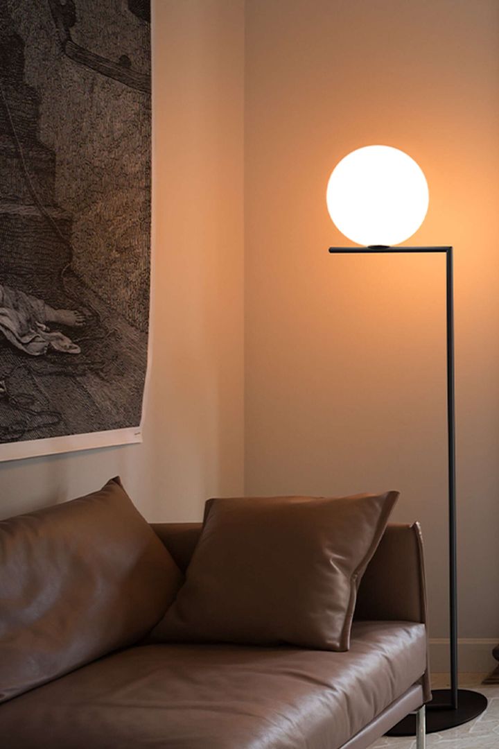 Från Flos kommer denna omtyckta golvlampa, IC Lights F1 har ett minimalistiskt formspråk med ett enkelt, rakt stativ och ett klot som ska symbolisera en sfär som nästan svävar. Här placerad intill en cognacsbrun lädersoffa.
