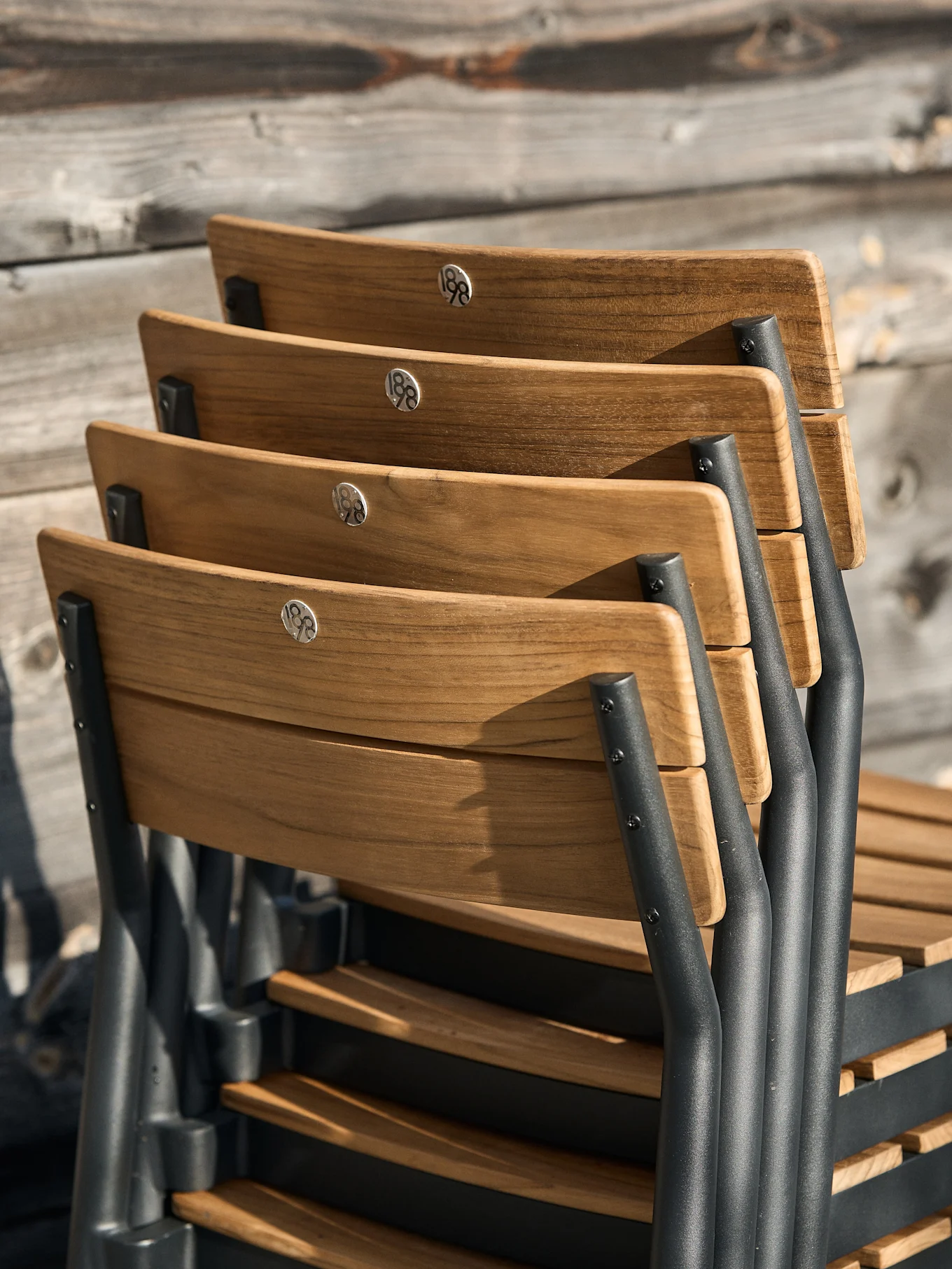 Staplade trästolar med mörkgrå ramar och '188'-detaljer på ryggstöden.