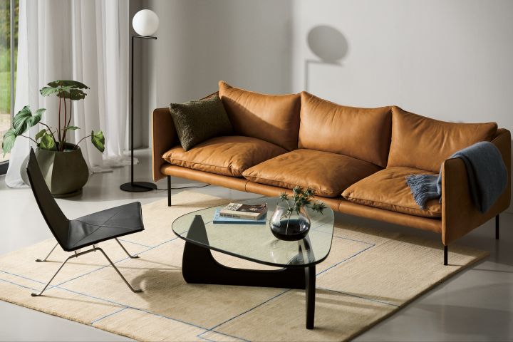 Rengör soffa i läder, som Tiki soffa från Fogia, här i cocgnacsfärgat läder placerad i vardagsrum med ljus matta, soffbord i glas och golvlampa från Flos.