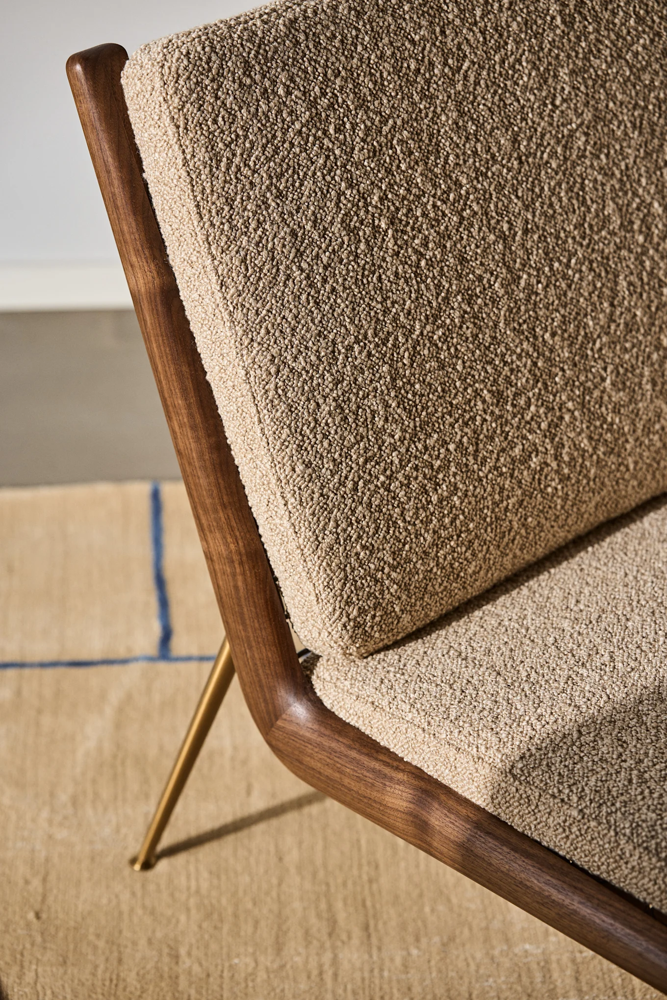 Bild som visar detaljer på Boomerang fåtölj från &Tradition. designad av Hvidt & Møllgaard. Här ser man detaljer i stolsryggen där bakstycket i valnöt möter den textila framsidan i beige.