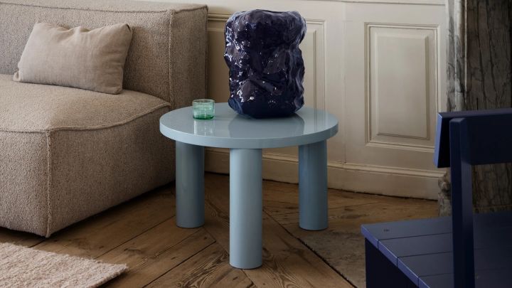 Så väljer du rätt soffbord, bild som visar Post soffbord i färgen Ice blue från varumärket Ferm Living, här placerad på trägolv bredvid en beige soffa, på bordet står en stor mörkblå vas.
