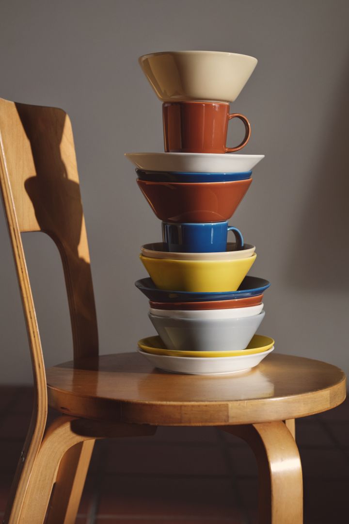 Teema porslin från Iittala i blandade färger staplade på stol.