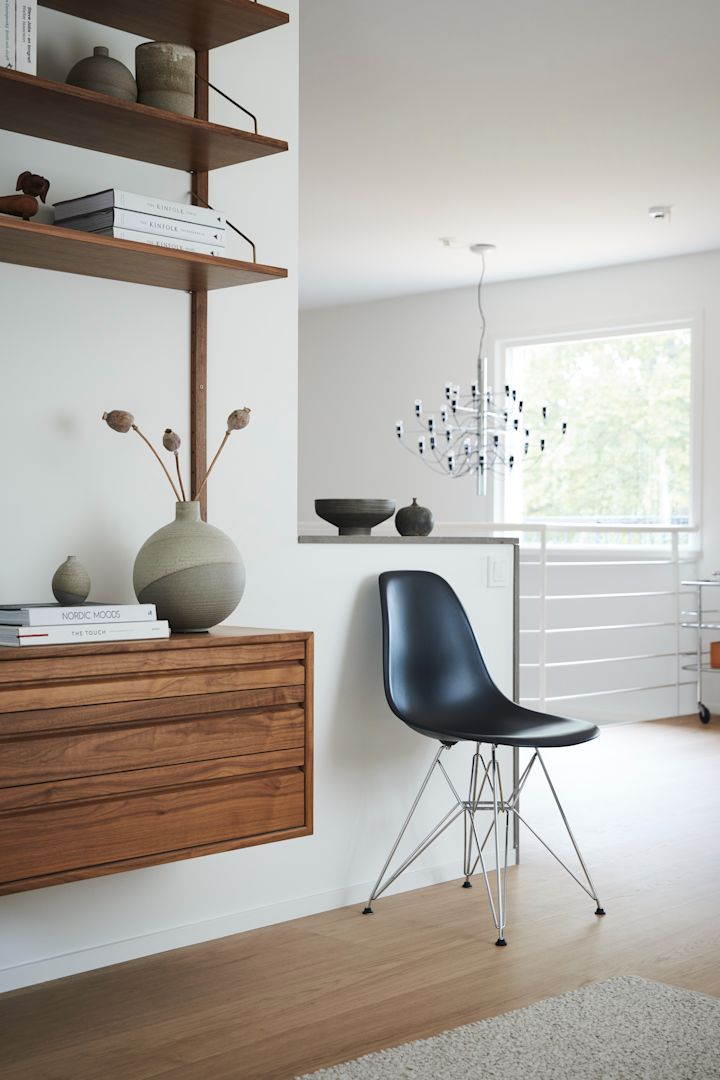 Hemma hos familjen Moser är det inrett i modernt och klassisk stil med en tydlig röd tråd i färger och materialval. På en av väggarna sitter hyllsystemet Royal från DK3 i trä och bredvid står en klassisk Eames-stol i svart från Artek. 