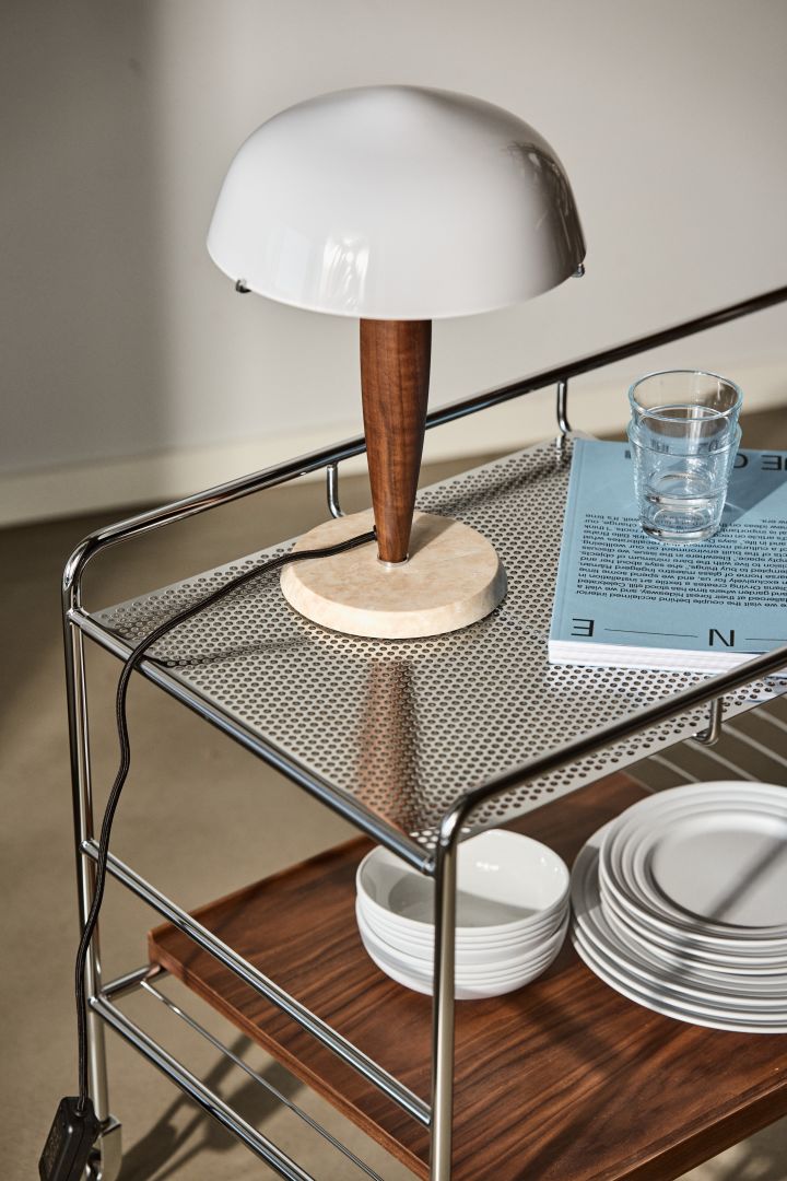 Bild som visar Herman bordslampa från &Tradition, en mindre lampa med fot i trä och marmor och med en skärm i vitt opalglas.
