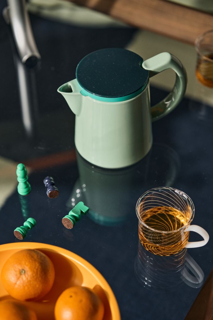 Bild som visar HAY Coffee kaffekanna i färgen mint. Kaffekannan står placerad på ett soffbord med glasskiva. Bredvid ligger schackpjäser i grönt och en liten glaskopp.