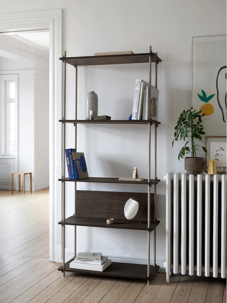 Mörkt trähyllsystem med fyra hyllor, ljusa metallstolpar, böcker och dekorationer i ett ljust rum.