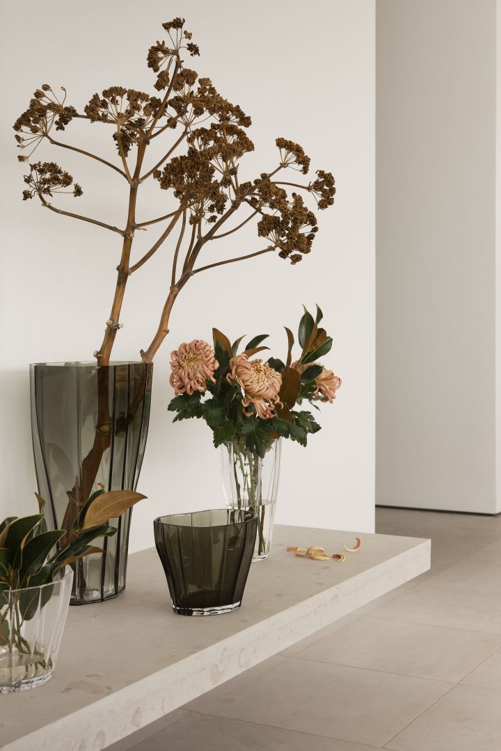 Bild som visar ett stilleben av Reed-vaser i olika storlekar och färger, med och utan blommor och kvistar i, placerade på ett lågt sideboard.