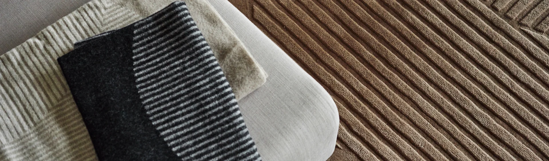 NJRD ullmatta i brunt och NJRD-pläd i brunt och beigt. 