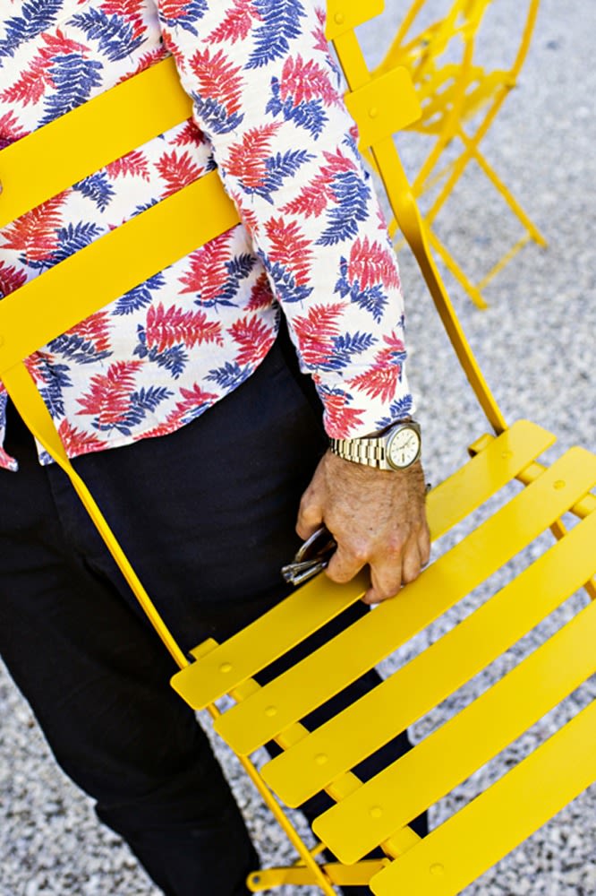 En man håller i en Bistro stol från Fermob i gul färg . 