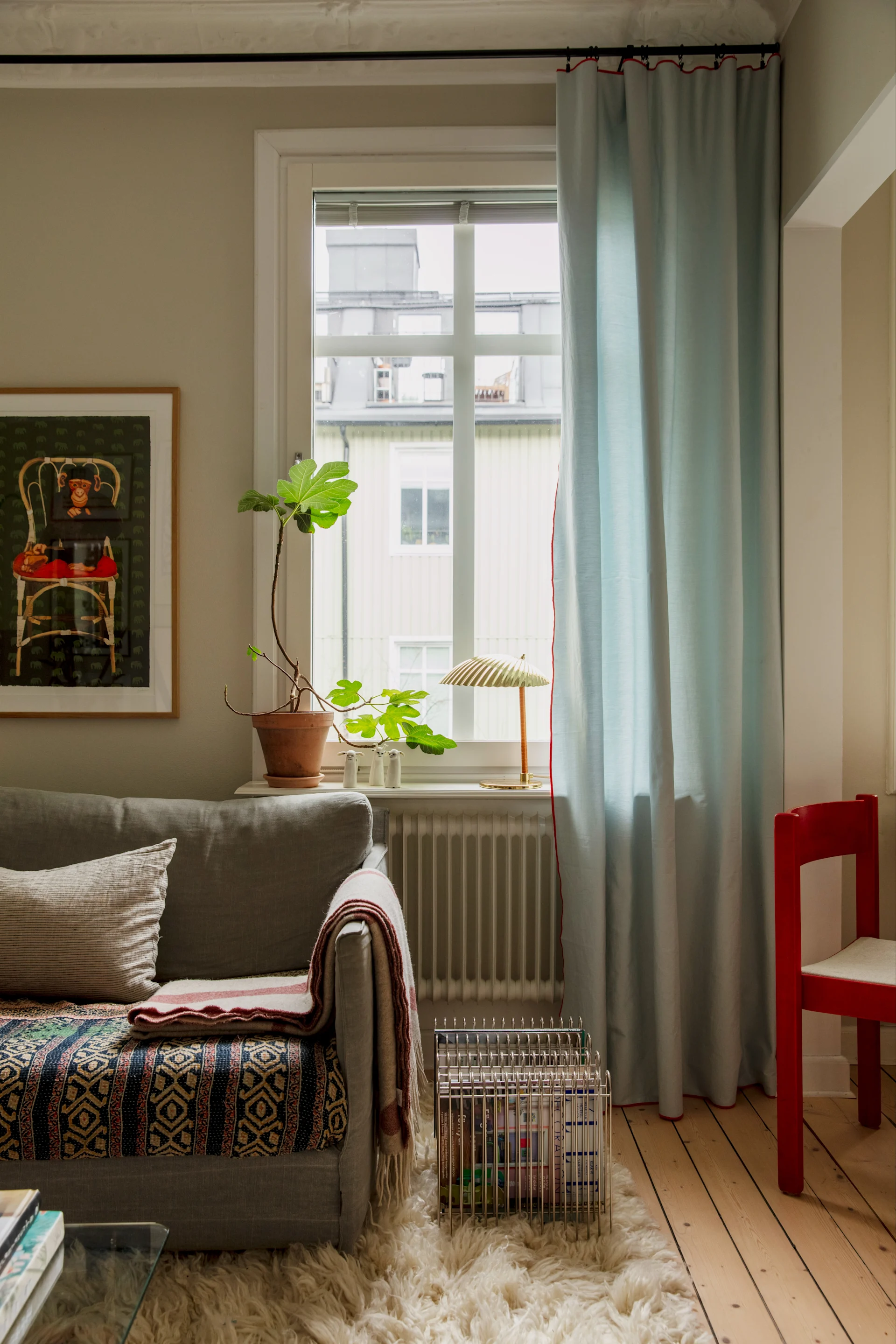 I vardagsrumsfönstret står den ikoniska 5321 bordslampan från Gubi, tillverkad i mässing.