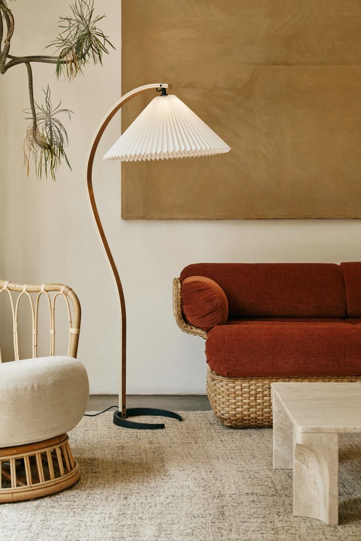 Elegant och klassisk är Timberline golvlampa från Gubi en härlig retro-aktig representant när det kommer till snygga golvlampor. Den organiska formen på stativet tillsammans med den plisserade skärmen prickar in alla rätt när det kommer till design. Här placerad i vardagsrum med röd soffa.