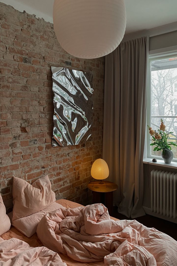 Mysig belysning hemma hos Elin Lannsjö, här Akari bordslampa från Vitra placerad i sovrum där den sprider ett stämningsfullt, varmt sken.