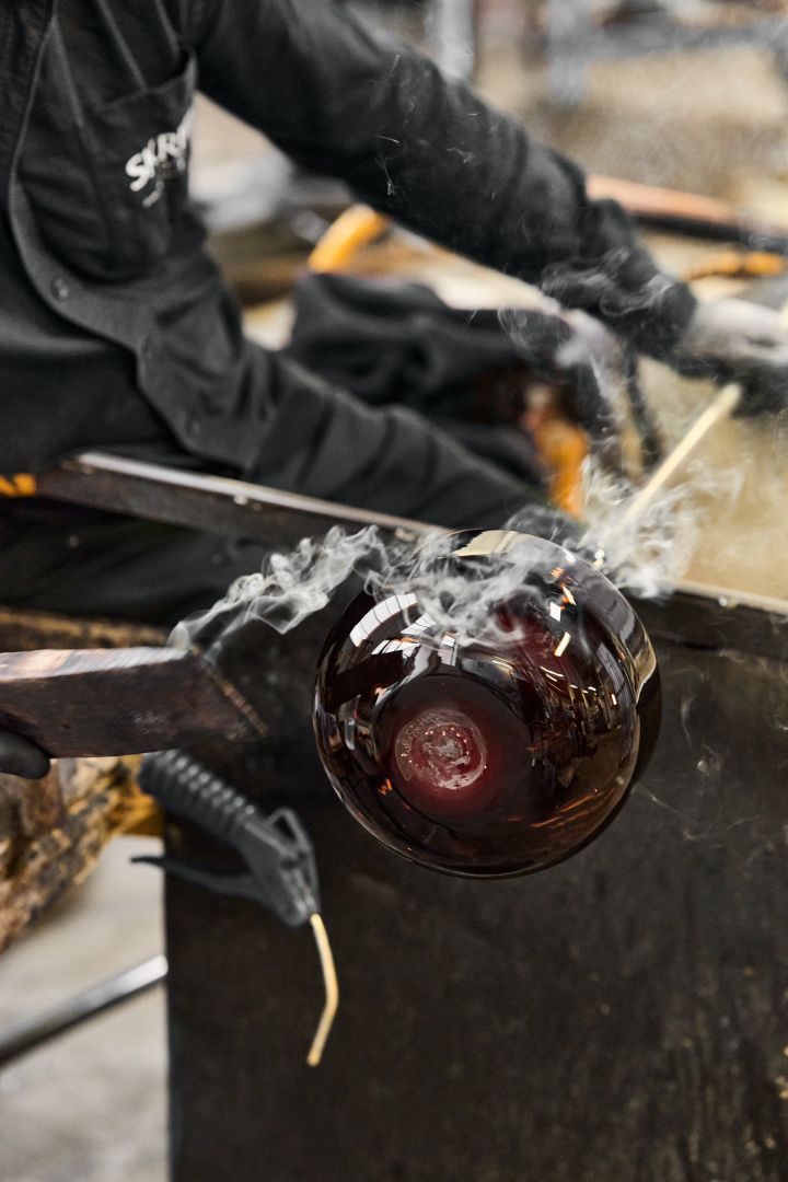 Bild som visar en Drummel-vas under tillverkning i glashyttan, här rykande varm från värmen i ugnen.