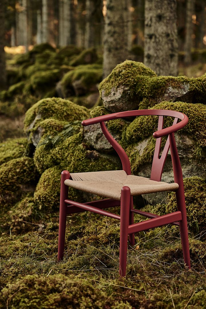 Y-stolen i färgen röd-brun av Hans J. Wegner placerad i mossa i skogen.