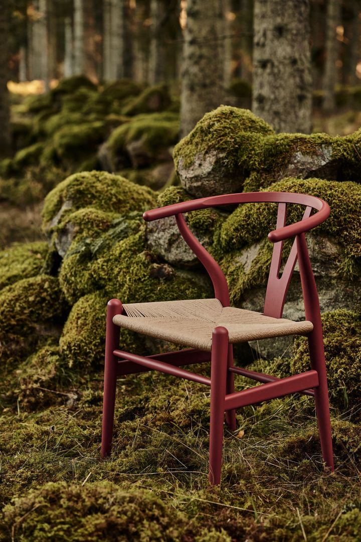 Y-stolen i färgen röd-brun av Hans J. Wegner placerad i mossa i skogen.
