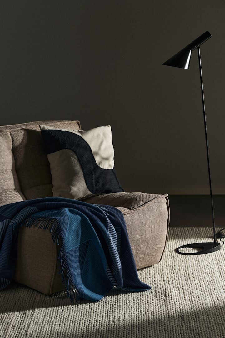 N701 fåtölj från Ethnicraft i beige tillsammans med Metrics pläd i blått från NJRD och en svart AJ golvlampa. Få men väl utvalda detaljer som ger sovrummet karaktär.