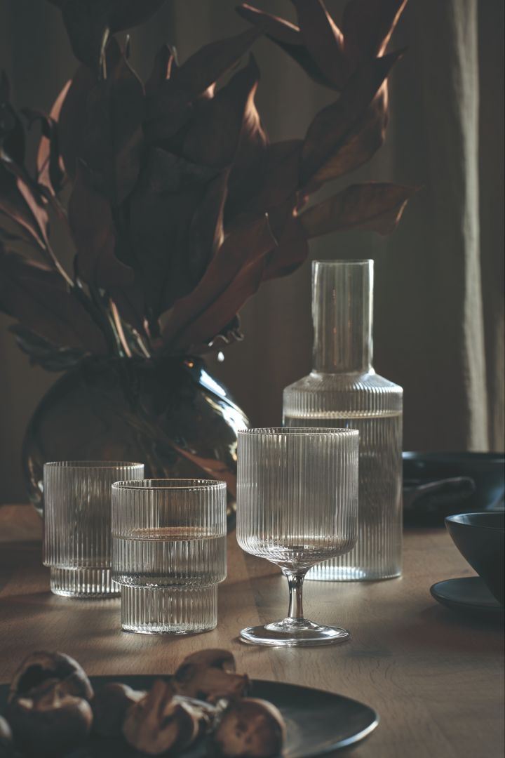 Matplats-inspiration med sober dukning i svart och med skira glas, här Ripple glas, vinglas och karaff från Ferm Living tillsammans med Water Swirl vas i gult.