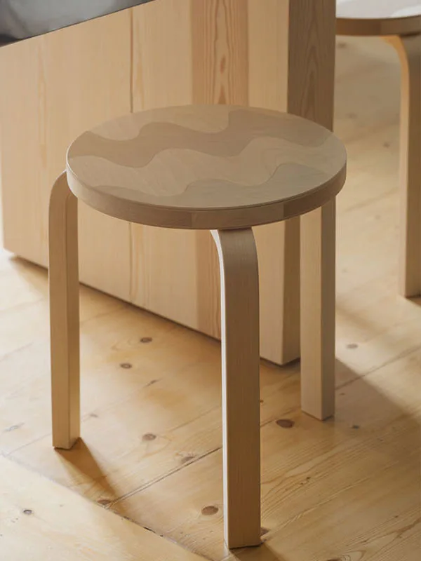 Ljus träpall med runda, böjda ben och ett vågigt mönster på sitsen.