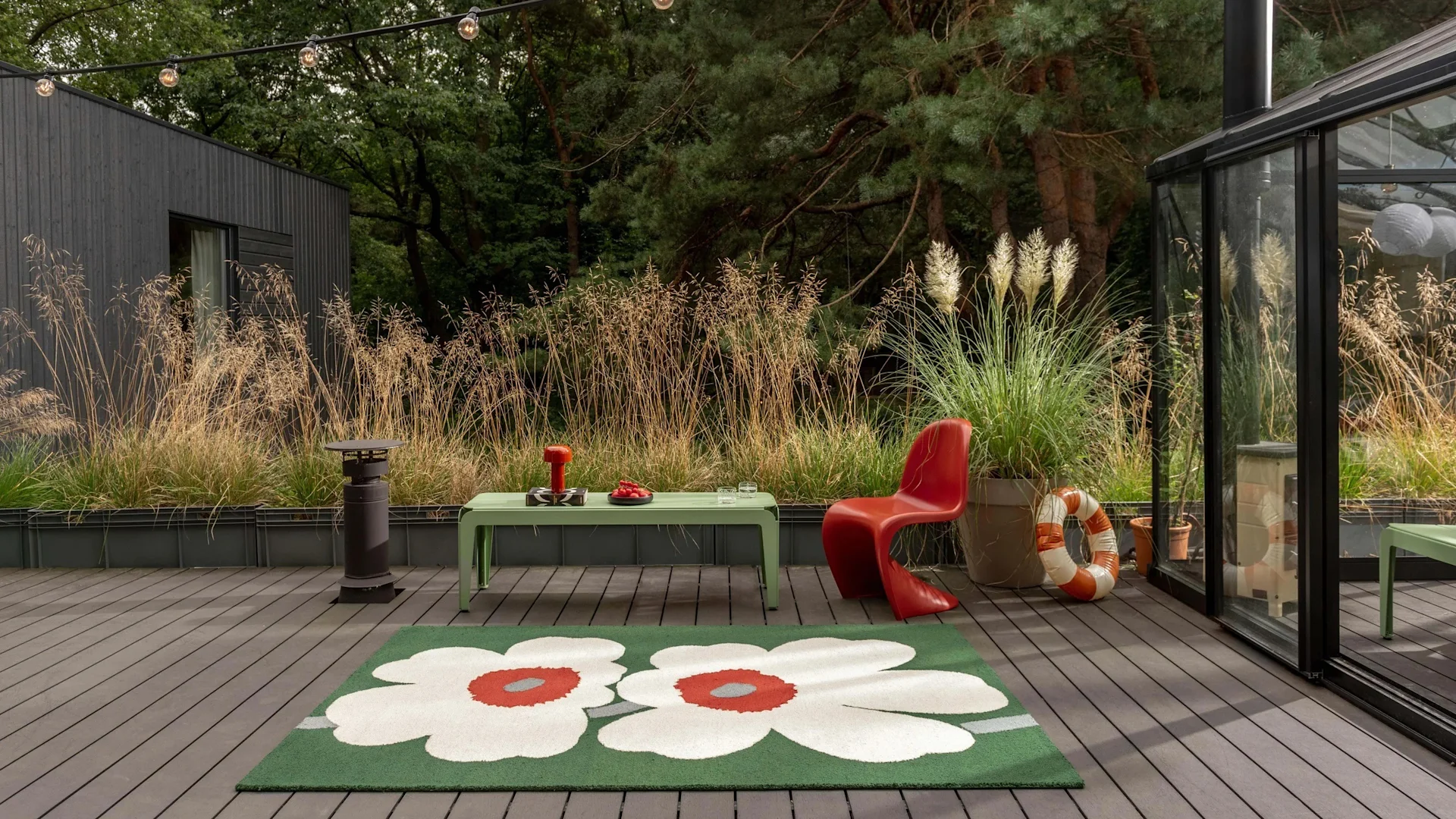 Bild som visar Unikko matta från Marimekko på uteplats, här i grönt med stora vita Unikko-blommor.