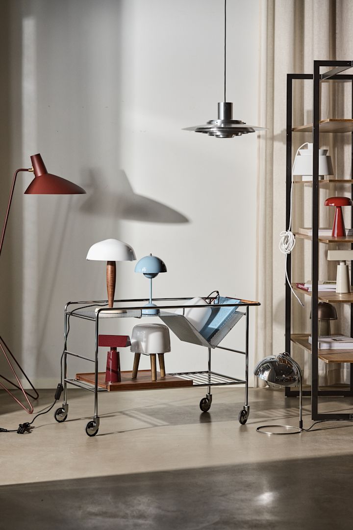 Bild som föreställer Alima förvaringsvagn i stål tillsammans med lamporna Tripod i rött, Flowerpot vp9 i ljusblått, Herman bordslampa och Milk bordslampa.