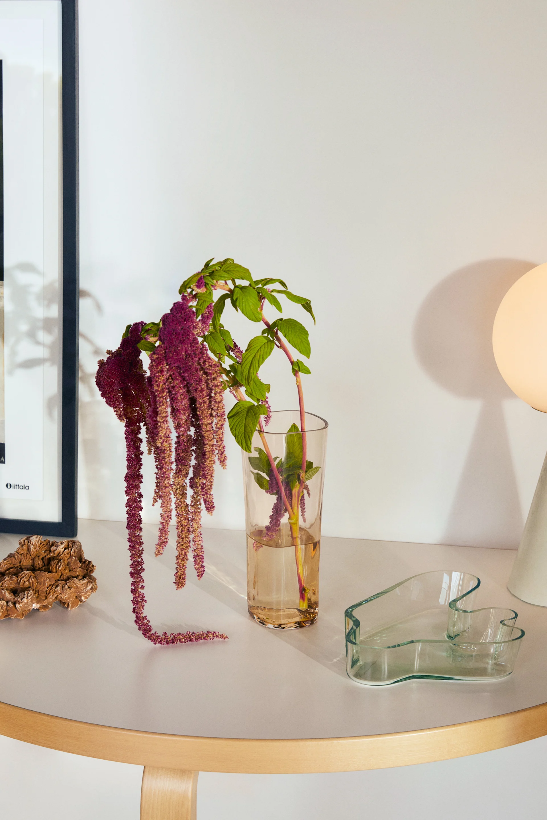 Alvar Aalto-vas i riobrunt, framtagen i samband med hans 125-årsjubileum från Iittala, placerad på månbord och fylld med hängande blommor.