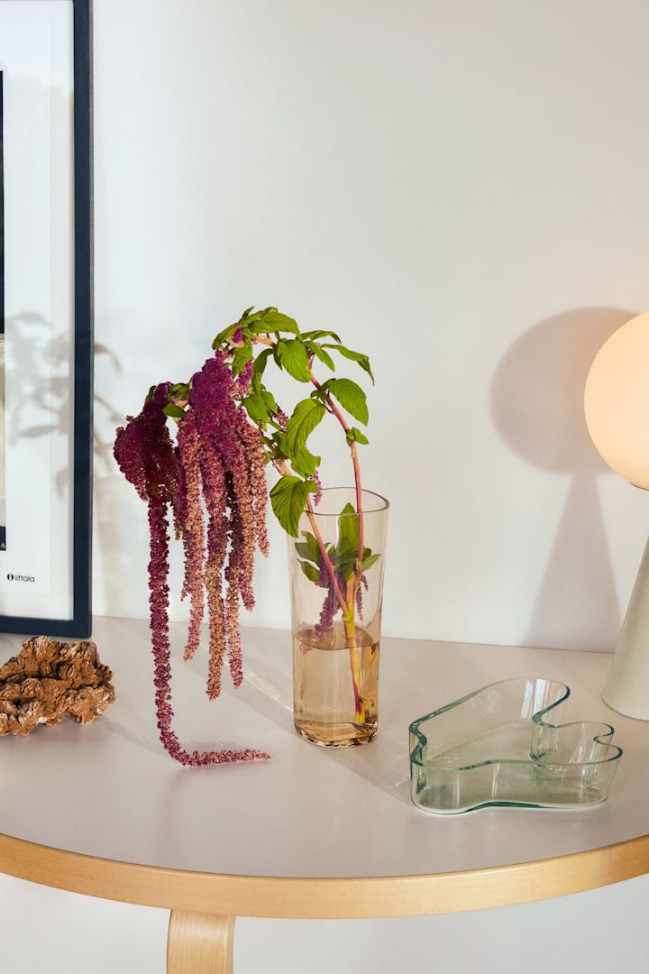 Alvar Aalto-vas i riobrunt, framtagen i samband med hans 125-årsjubileum från Iittala, placerad på månbord och fylld med hängande blommor.