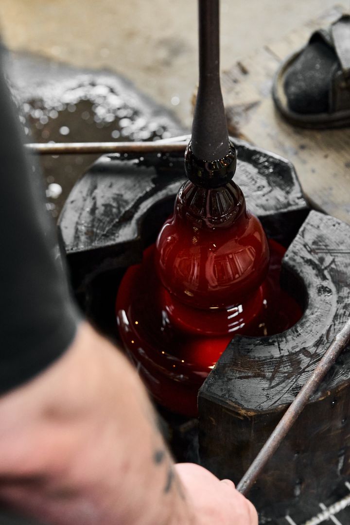 Bild som visar Drummel vas i sin form när den blir till, häri bärnstensfärgat glas. Bilden är från Skrufs Glasbruk och hytta.