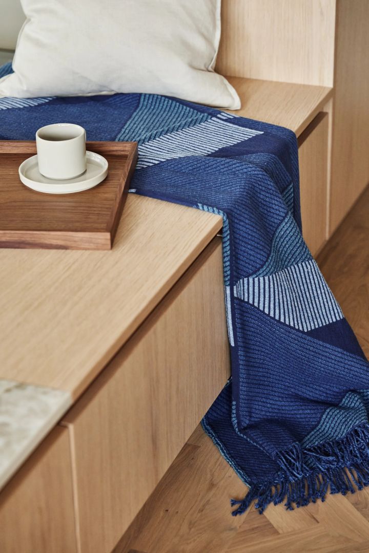 Inred med textilier för att mjuka upp ditt snygga vardagsrum, som med Metrics bomullspläd i blått från NJRD.