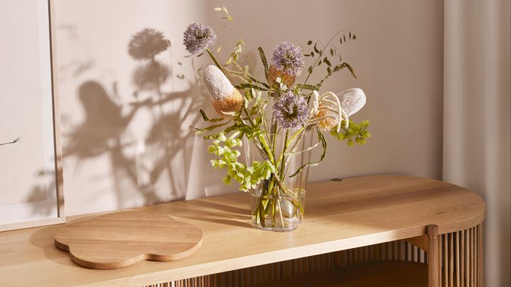 Alvar Aalto jubileumsvas från Iittala fylld med blommor, placerad på sidobord i ek.