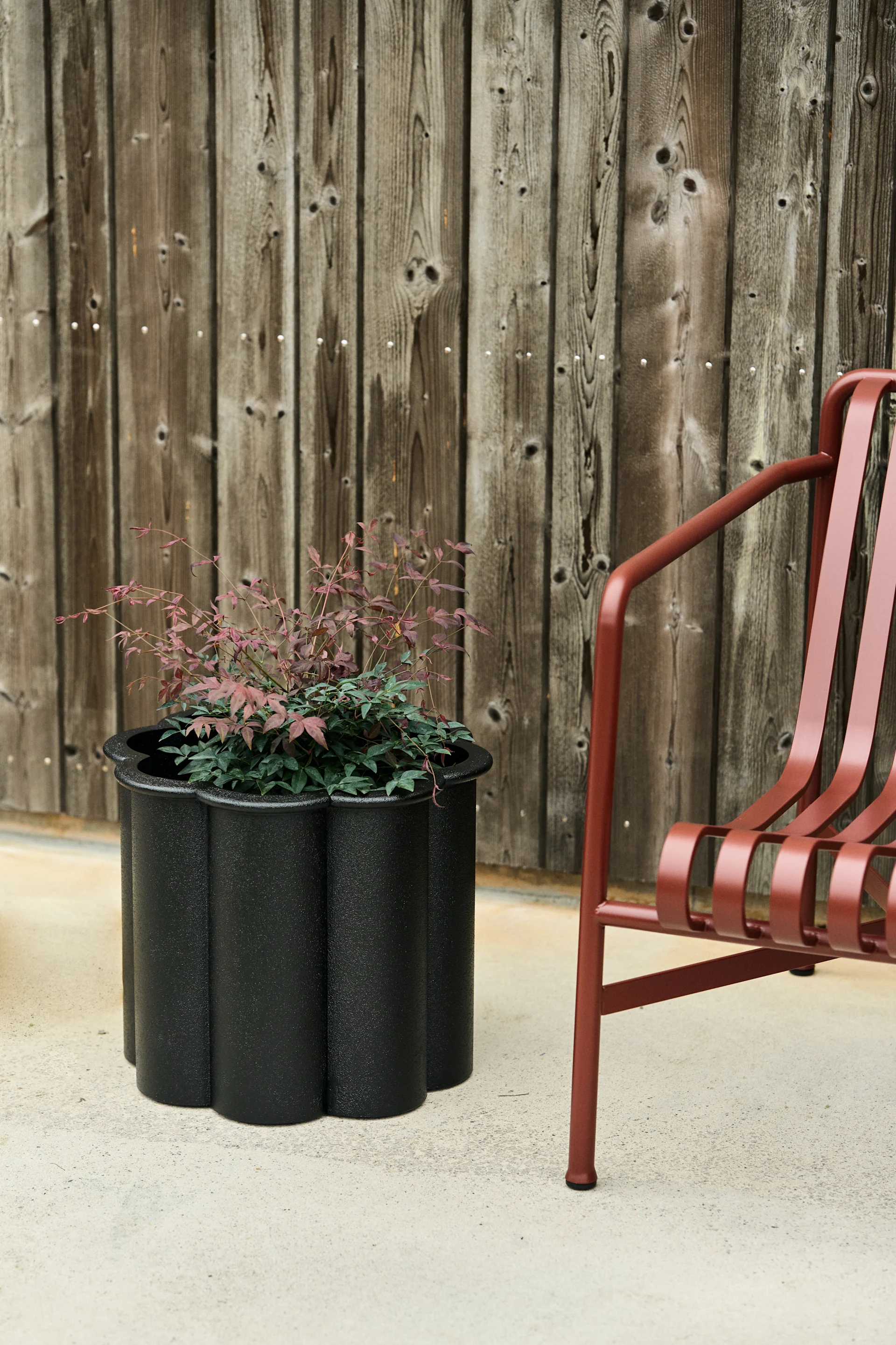 Gråsippa kruka i svart från Byarums bruk bredvid Pallisade stol i rött från HAY: