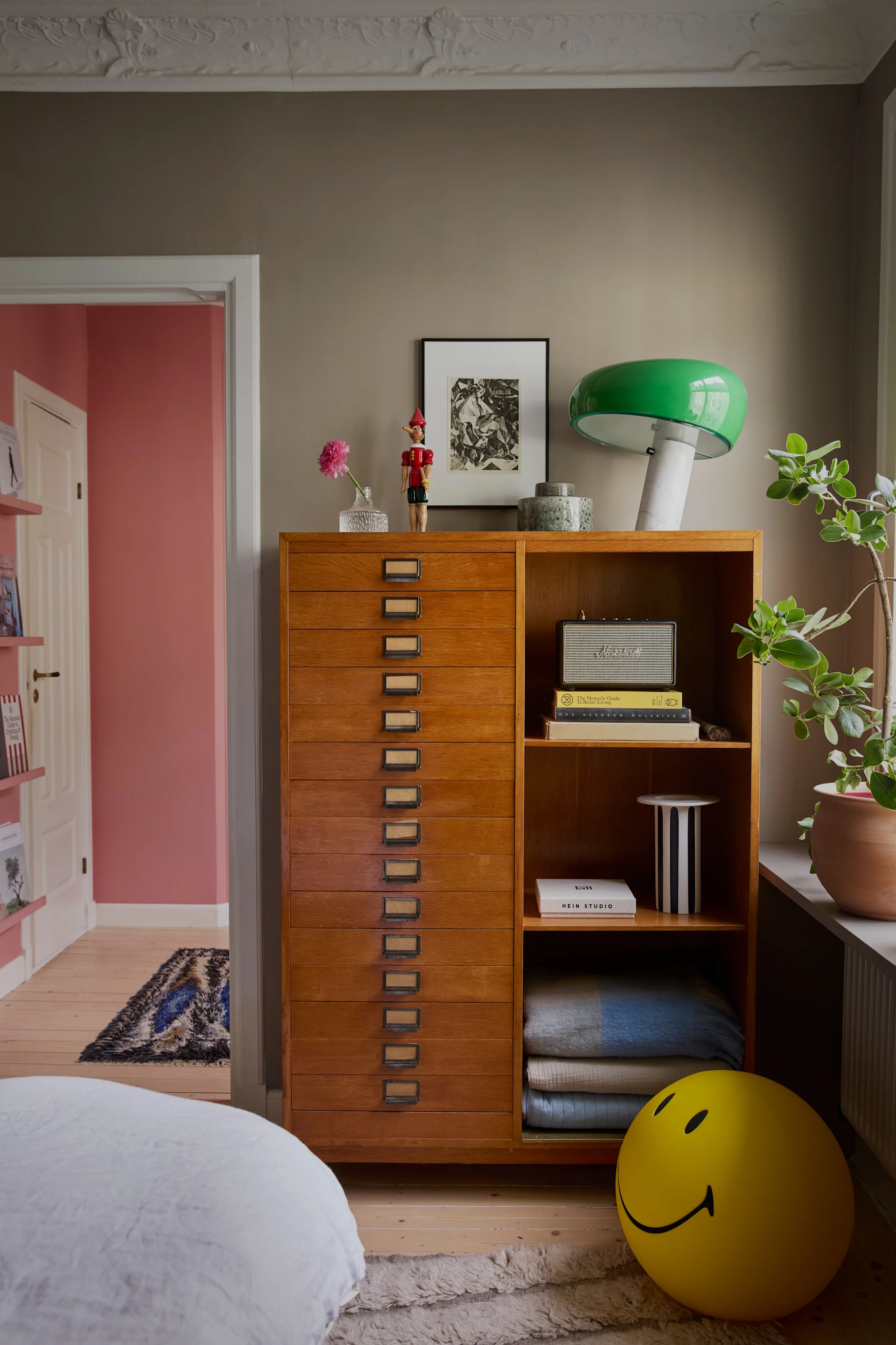 På ett gammalt arkivskåp i trä står en grön Snoopy-lampa från Flos.