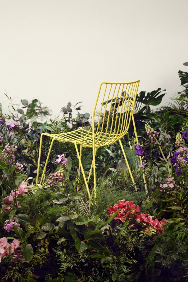 Tio stol i gult från Massproductions placerad på en äng av blommor
