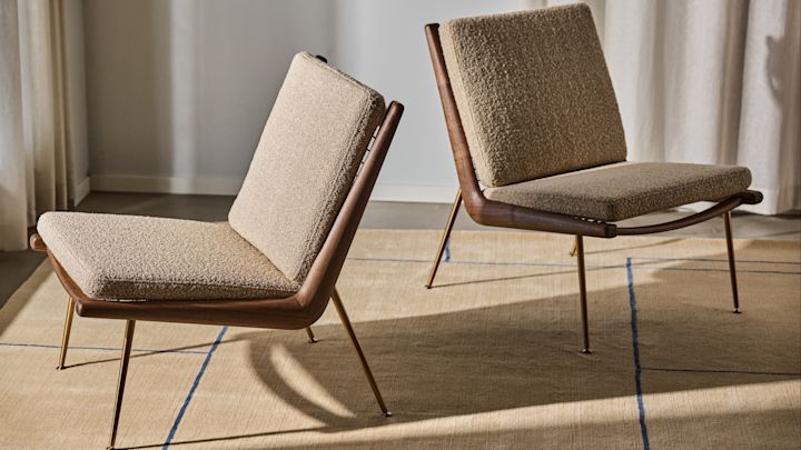 Bild som visar två Boomerang-fåtöljer av designduon Hvidt & Mølgaard, här i beige med valnötsben stående på Cruise AP12 matta i beige med linjerat mönster i blått.