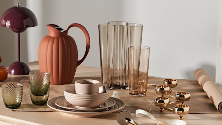 Presenttips till den designintresserade och tips på klassiska examenspresenter uppdukade på ljust träbord. Här står Flowerpot portabel lampa i färgen dark plum tillsammans med Bernadotte termoskanna i terracotta, Alvar Aalto vas i rio brun och Lines porslin i beige från NJRD.