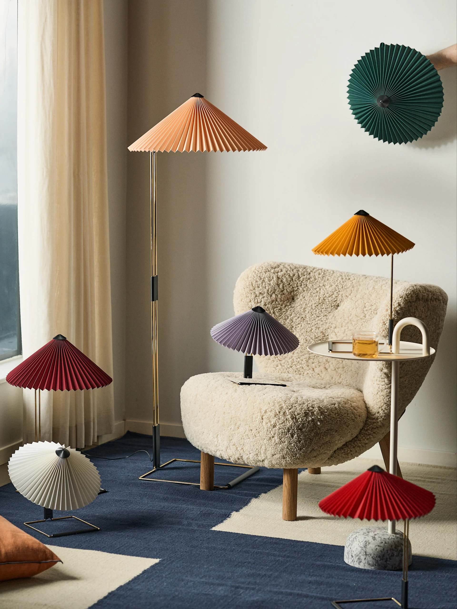 Bild som visar Matin-lampor i olika färger och modeller från HAY tillsammans med Little Petra fåtölj i vitt fårskinn från &Tradition.