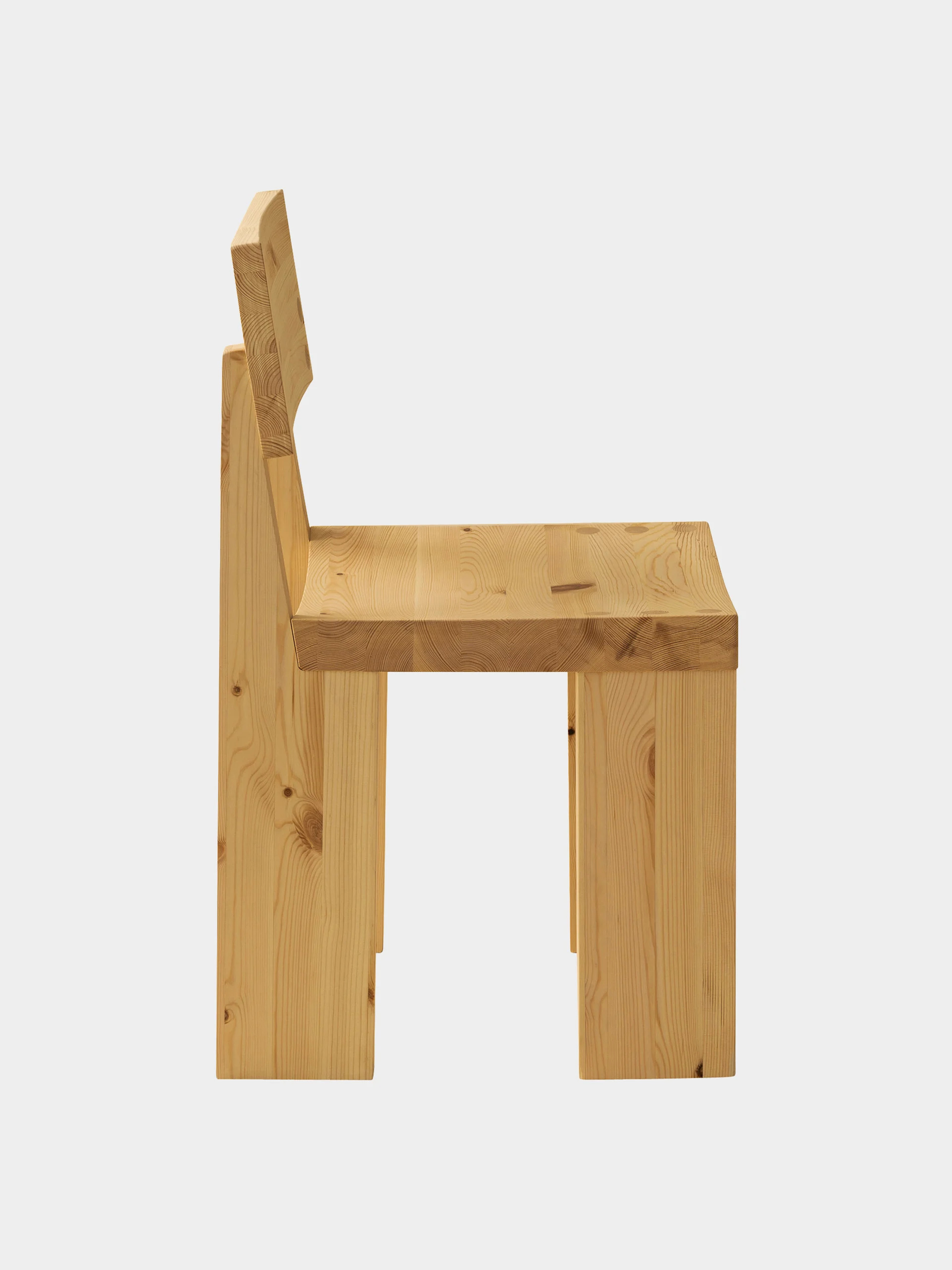 En minimalistisk trästol sedd från sidan, med tjockt, ljust trä med synliga ådringar och kvistar.