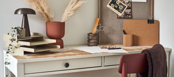Hemmakontor i vitt med detaljer i varma, jordnära toner, vitt skrivbord med vinröd stol.