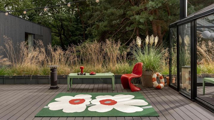 Bild som visar Unikko matta från Marimekko på uteplats, här i grönt med stora vita Unikko-blommor.