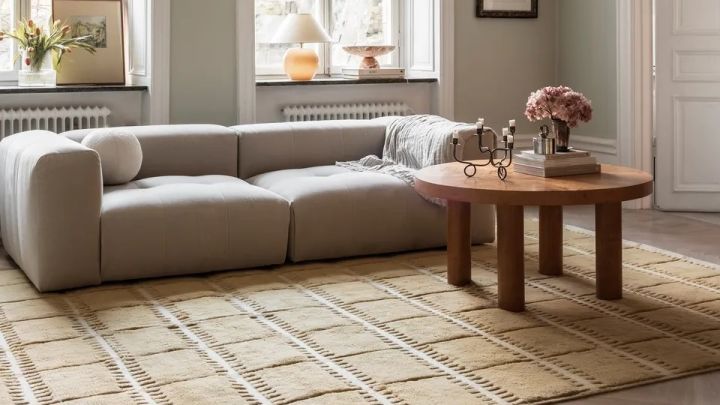 Bild som visar ljust vardagsrum med beige soffa, på golvet ligger en stor Lilly ullmatta i senapsgult från varumärket Layered.