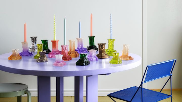 Rocky Baroque-serien av Hanna Hansdotter består av kolonn-liknande ljusstakar i massivt glas som färgats på unika sätt i olika färger. Här samsas hela kollektionen på ett lila, runt bord.