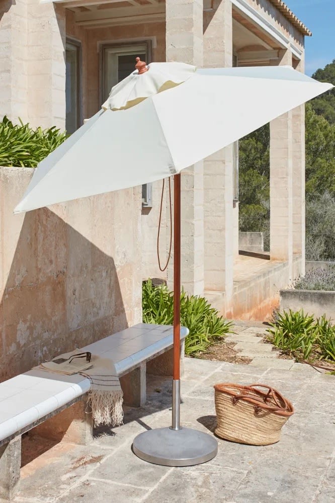Messina parasoll i vitt från Skagerak tillsammans med Capri parasollfot, ett exempel på litet parasoll som passar uteplatsen, terrassen eller trädgården.