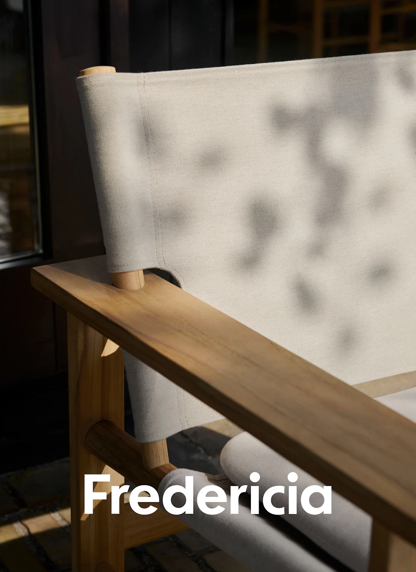 Stol med ljust canvastyg, träarmstöd och 'Fredericia' text längst ner.