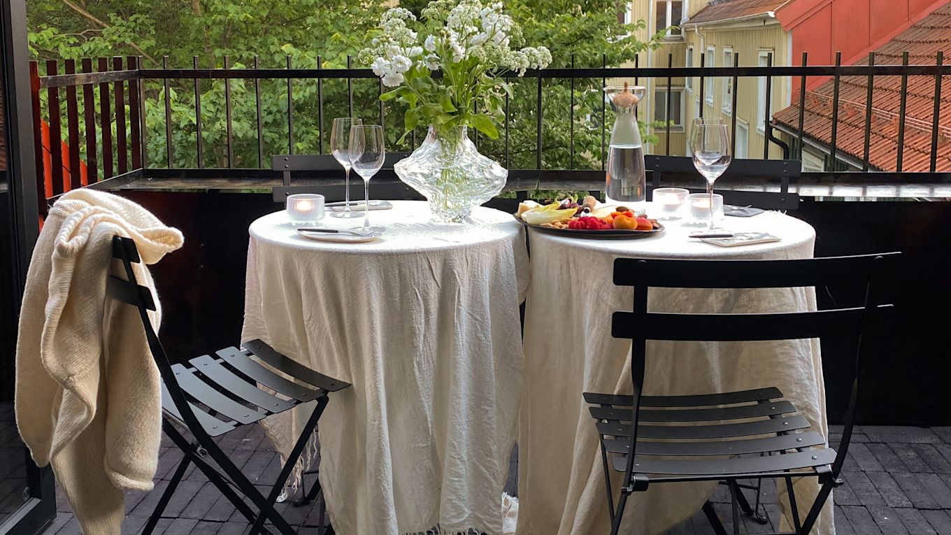 Uppdukat med Bistro caféstolar och bord från Fermob på Elin Lannsjös balkong. Här med vita linnedukar, ljuslyktor, vas me blommor, vinglas och fat med frukt och nötter.