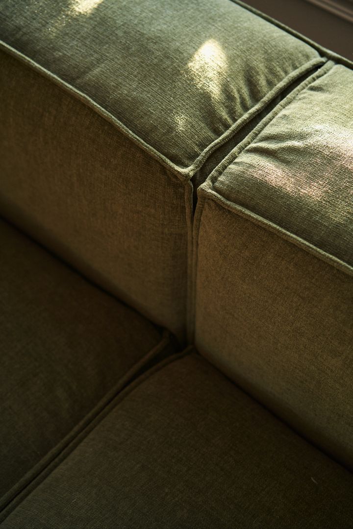 Rengöra soffa i tyg bör göras regelbundet för att soffan ska hålla sig fräsch och fin, här närbild på grön soffa med rejäl sittdyna.