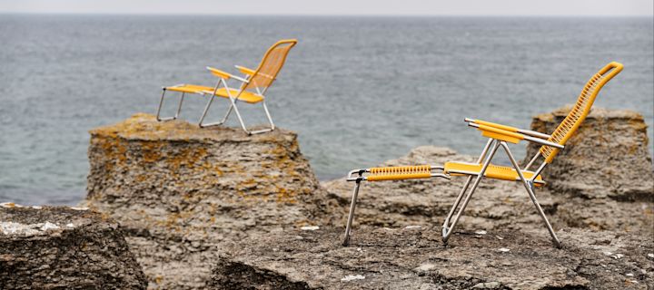 Snygga solstolar & sköna solsängar - bild som visar en gul Spaghettil solstol från Fiam, placerad på raukar med havet framför.